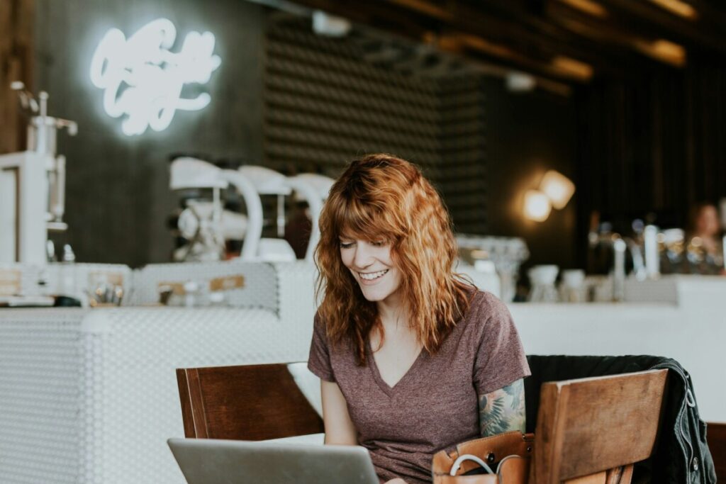 person sitting at the cafe starring a laptop with smiling